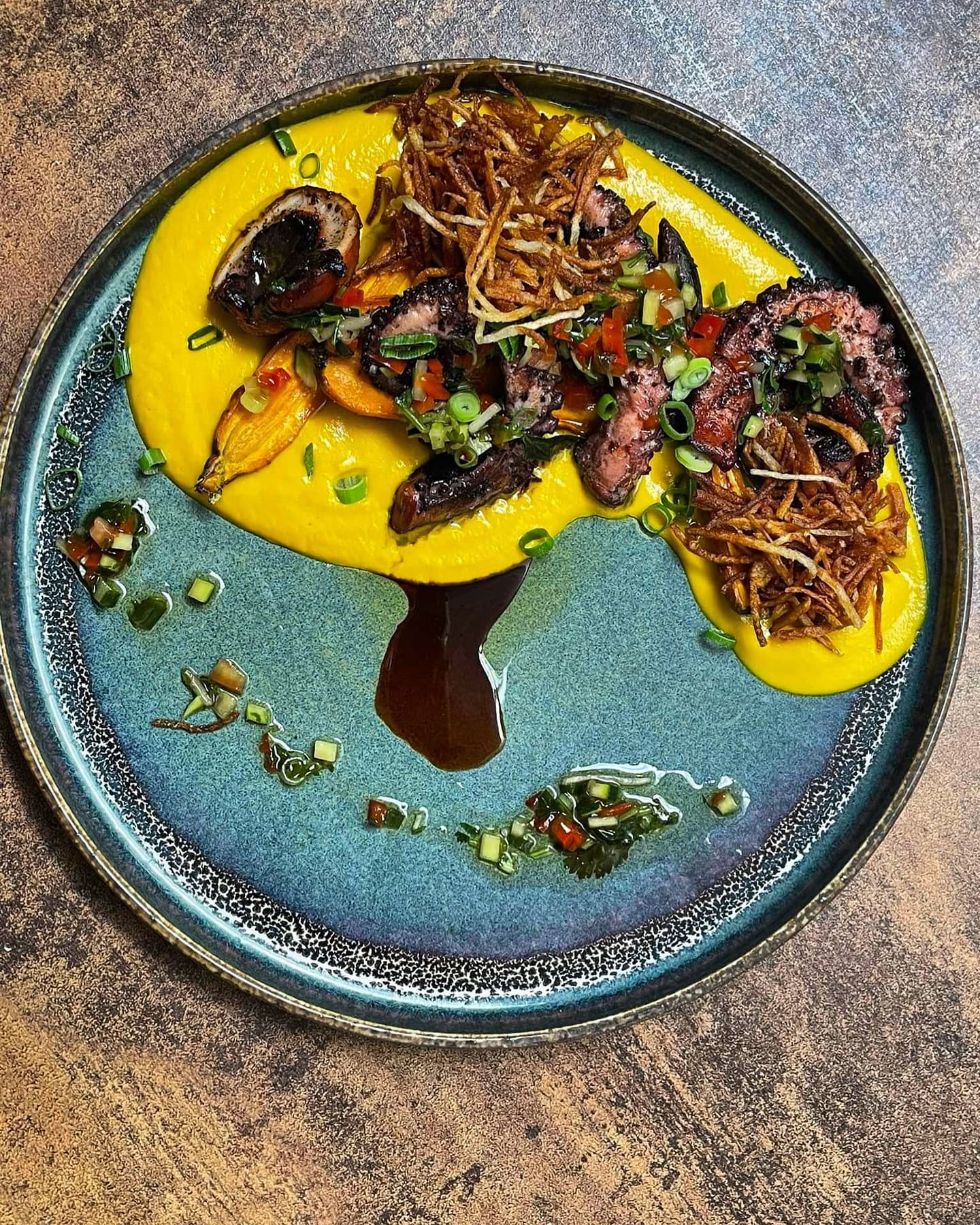 Poulpe rôti sur purée de patate douce, assiette céramique bleue